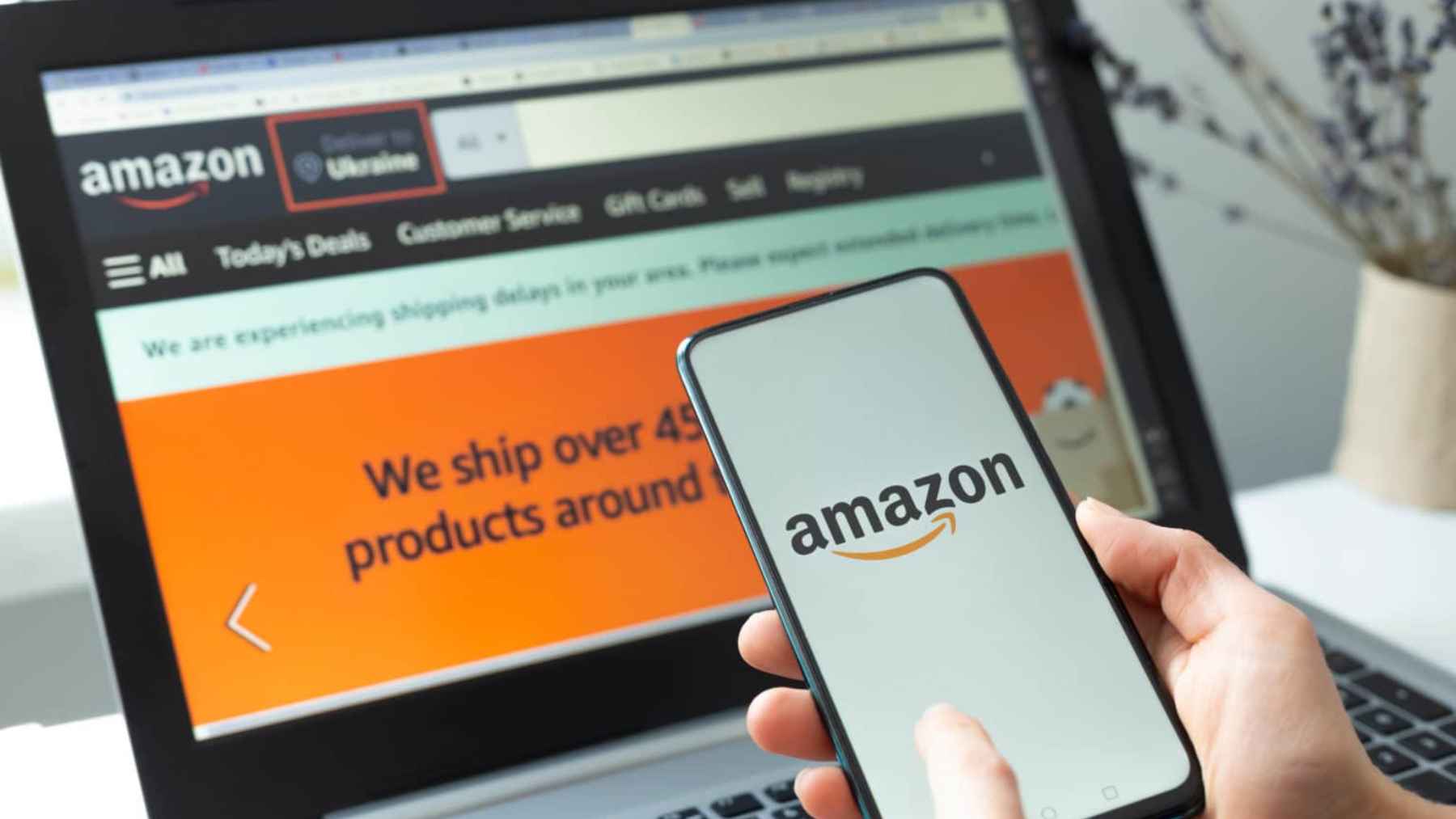 Person holding a smartphone with Amazon app in front of a laptop showing Amazon website, representing mobile strategy and AI integration