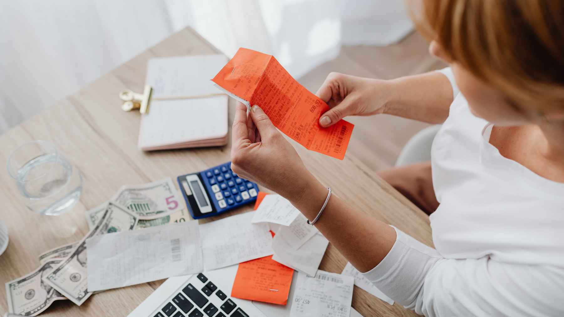 Woman reviewing bills, receipts, and cash at home as rising healthcare costs push more Americans to consider moving abroad