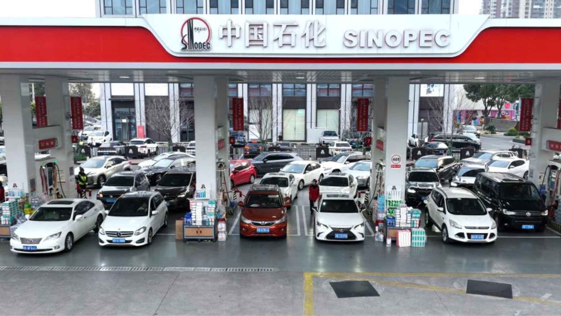 A crowded Sinopec gas station in China with numerous cars lined up at fuel pumps under a red and white canopy