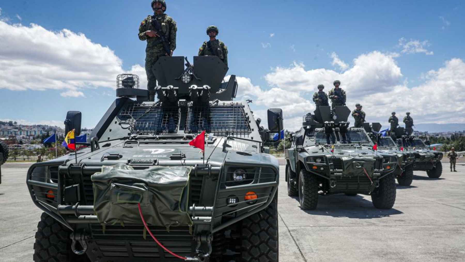 Ecuadorian soldiers standing on top of green Otokar Cobra II armored tactical vehicles during a formal military presentation.