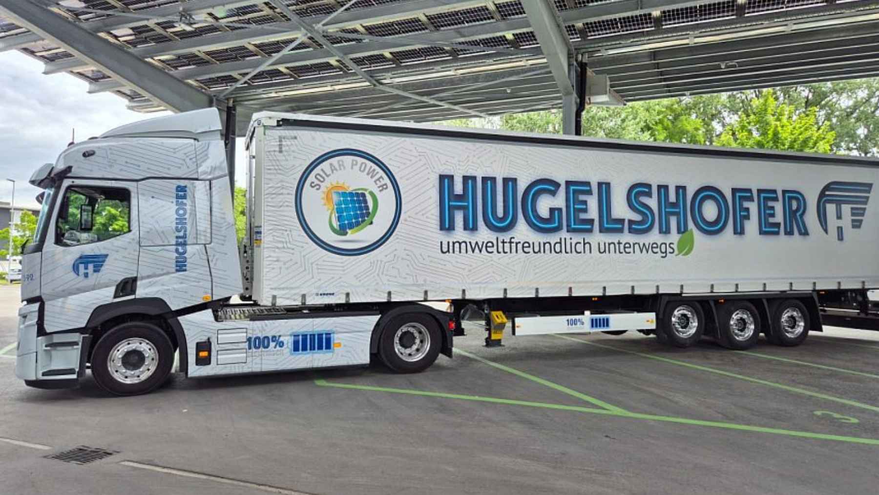 Hugelshofer electric truck parked under solar panel canopy at a charging station in Switzerland
