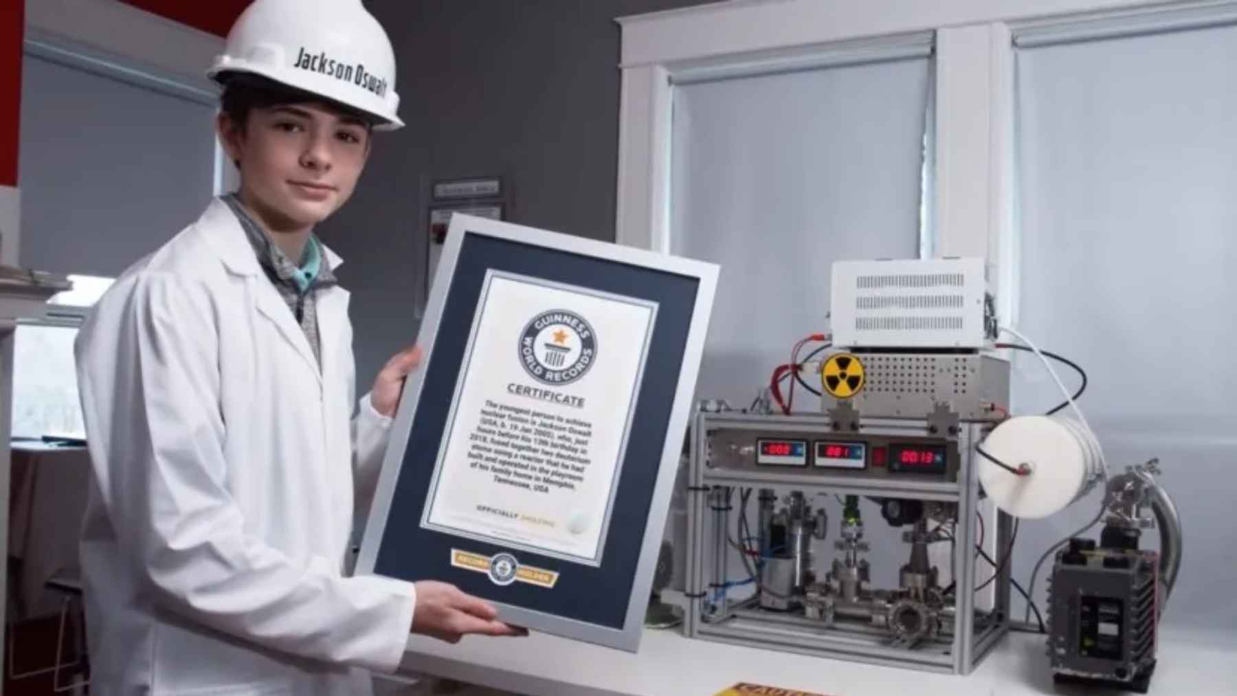 Teen scientist Jackson Oswalt holding a Guinness World Records certificate next to his homemade fusion reactor experiment.