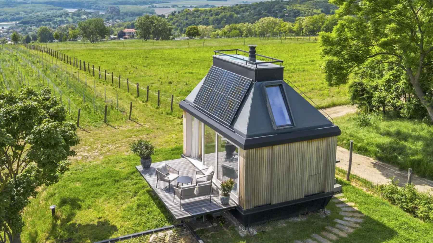 Small off-grid cabin with glass walls and fold-out terrace powered by solar energy in a natural setting