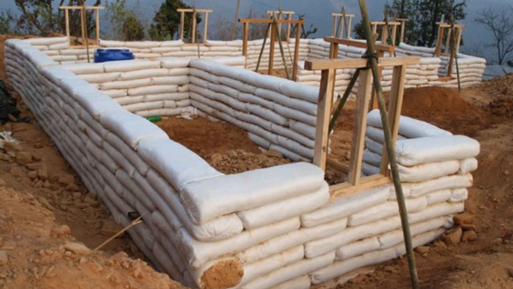 Superadobe house under construction using stacked soil filled sacks instead of traditional bricks.