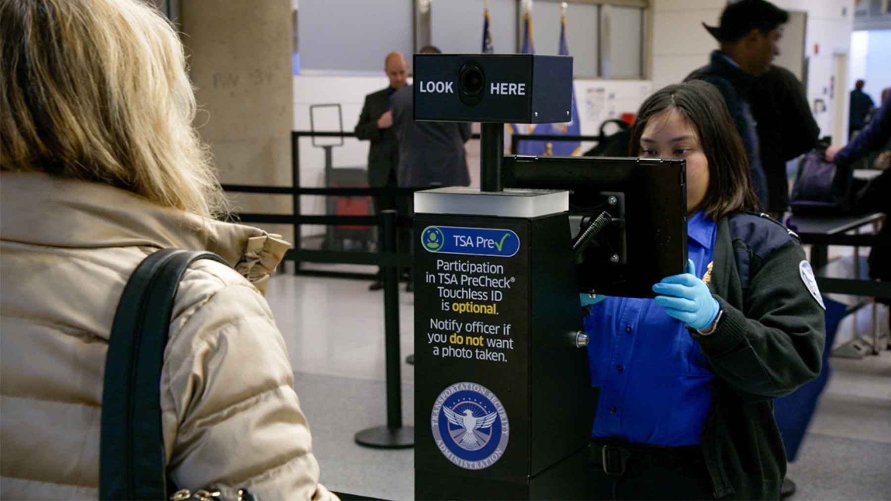 Airport security checkpoint where TSA officers verify traveler identification before passengers enter the screening area.