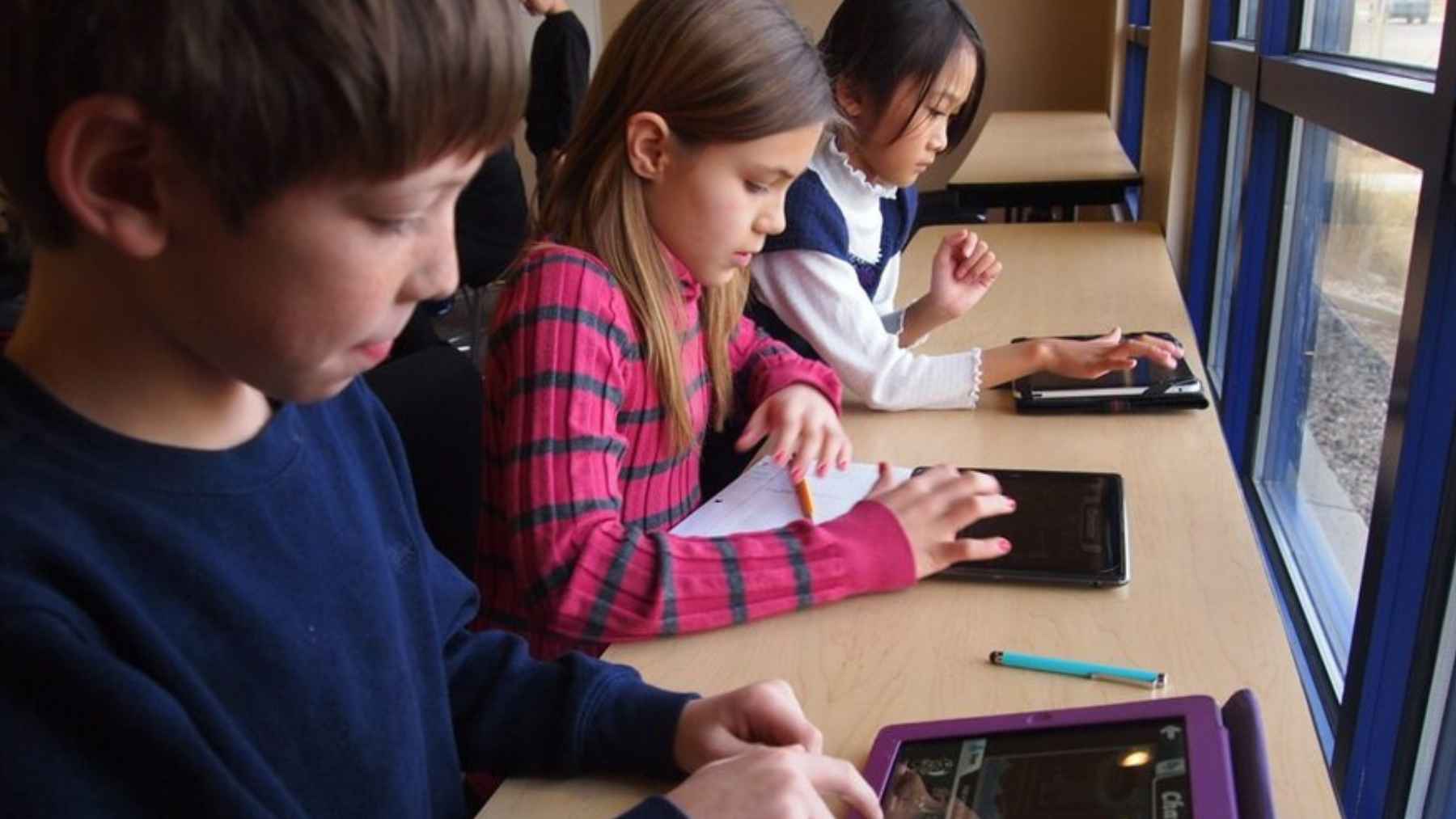 Students using laptops and tablets in a classroom as schools expand one to one digital learning programs.