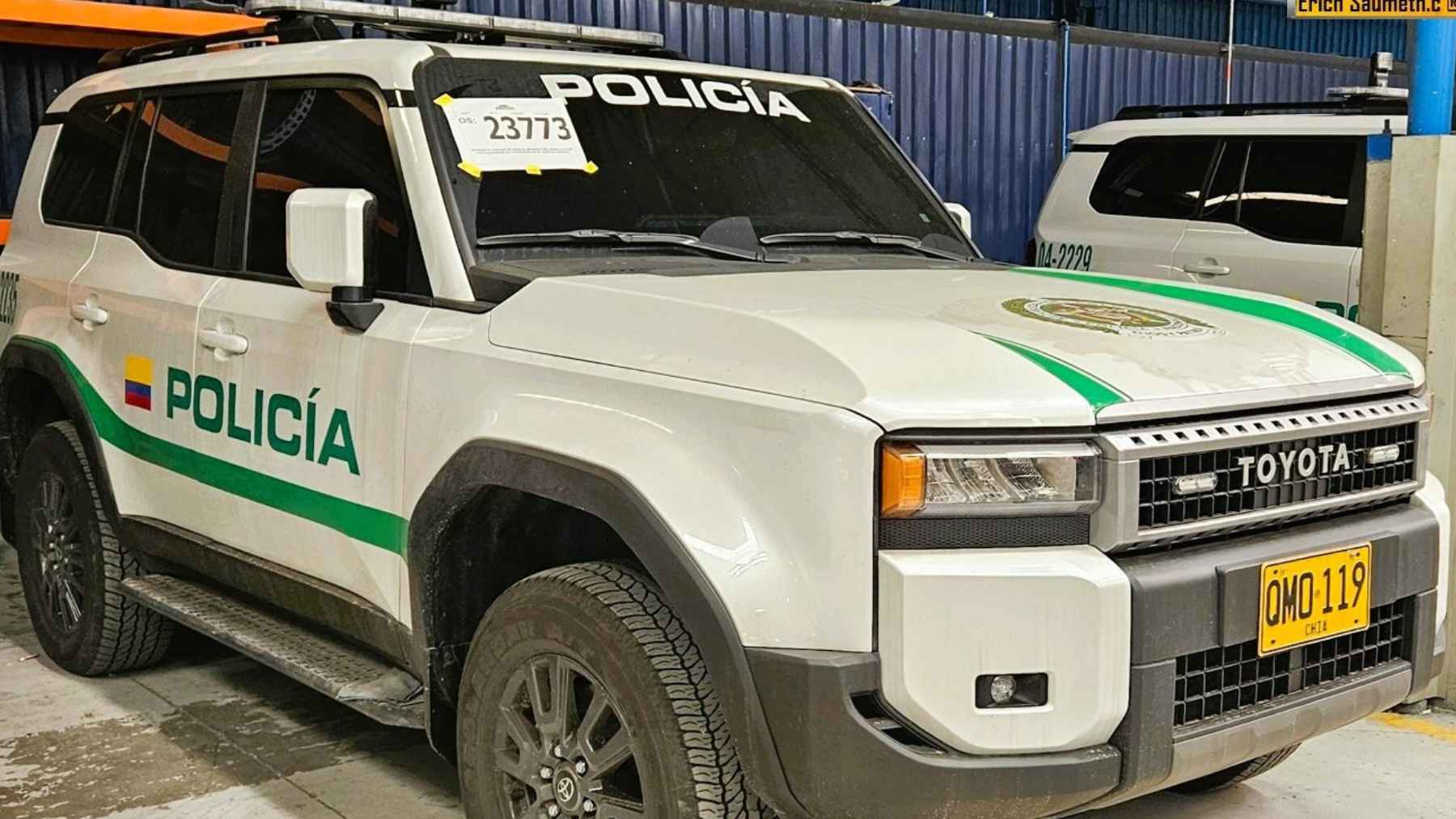 A white and green Colombian National Police Toyota Land Cruiser Prado armored SUV parked in a maintenance garage.