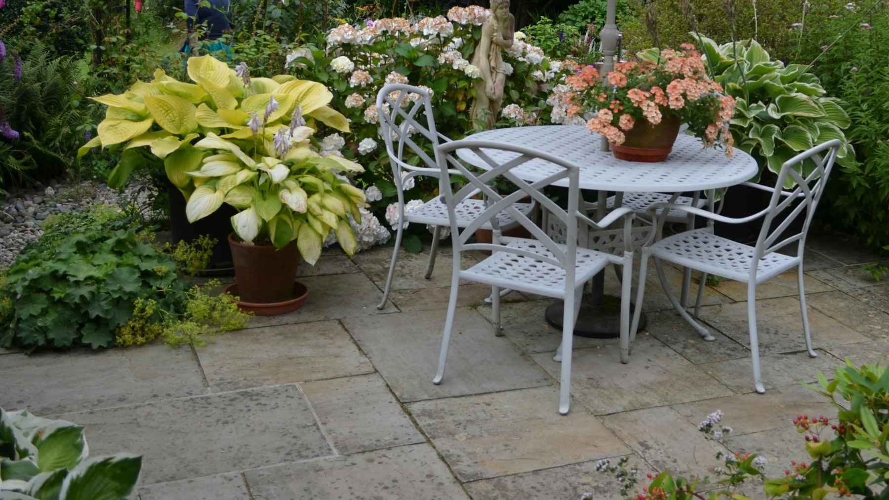 Natural stone patio with irregular pavers in a residential backyard as an eco-friendly alternative to concrete