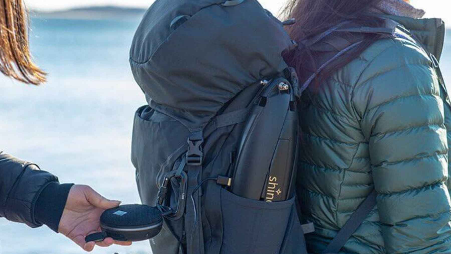 Person attaching a compact portable wind turbine to a backpack for off-grid charging during outdoor travel