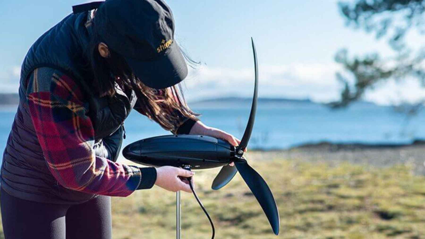 Compact portable wind turbine generating electricity outdoors, designed to charge devices in low-light or off-grid conditions