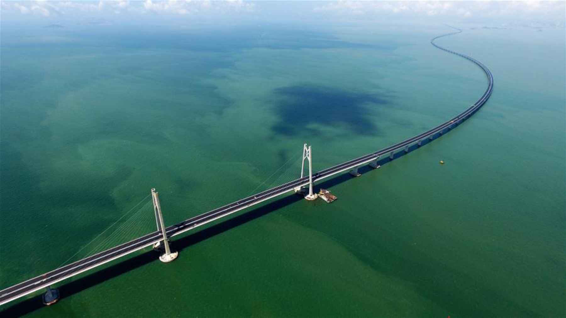 An aerial perspective of the Shenzhen-Zhongshan Link's suspension bridge section, showing the white pillars and a long, curving road over the sea.