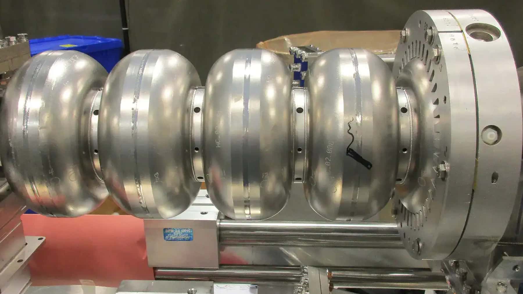 Componente metálico de un acelerador de partículas en un entorno de laboratorio o instalación científica.