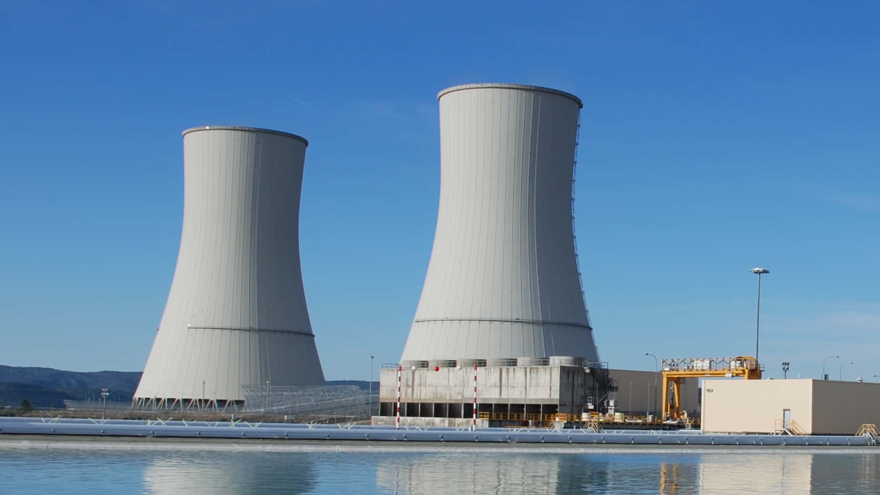 Torres de refrigeración de la central nuclear de Almaraz junto a una lámina de agua en una imagen exterior diurna.