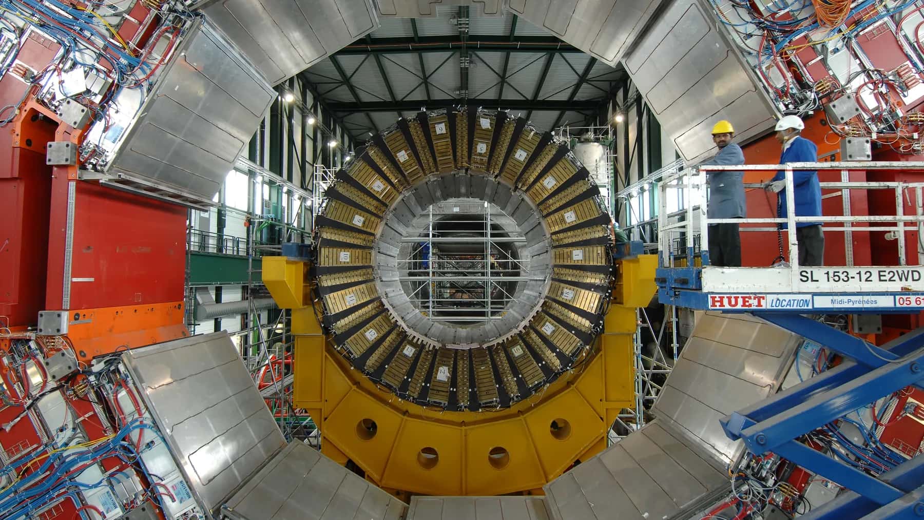 Interior de un detector del Gran Colisionador de Hadrones con técnicos trabajando en la instalación.