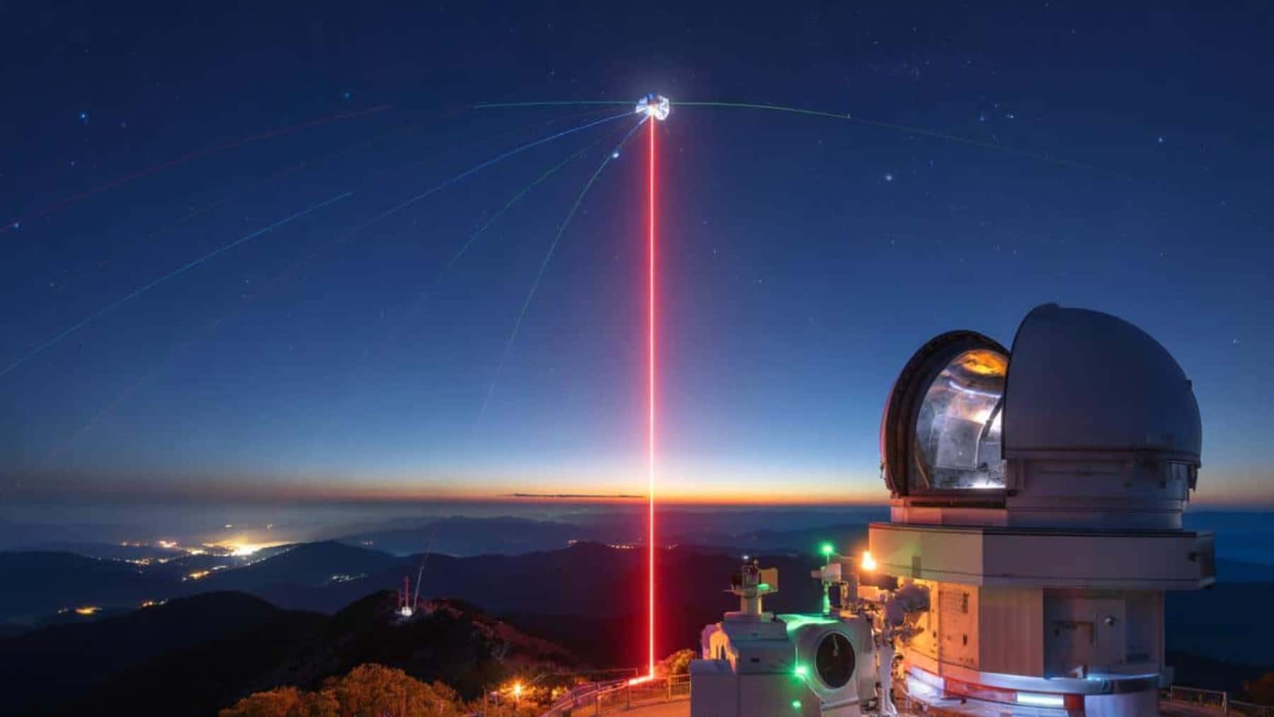 Observatorio astronómico en una montaña emitiendo un haz láser rojo hacia un satélite en el cielo al anochecer.