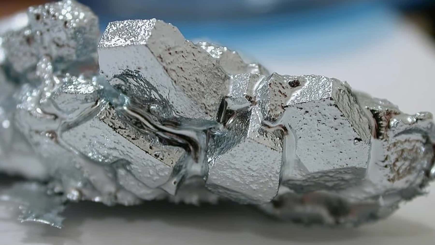 Muestra de cristal de galio metálico con superficie brillante y estructura sólida en primer plano.
