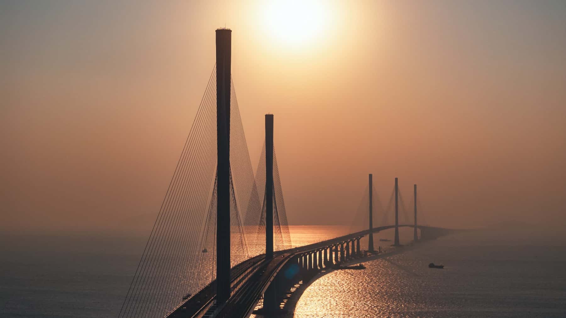 Vista del puente Hong Kong-Zhuhai-Macao al atardecer sobre el mar con sus grandes torres atirant