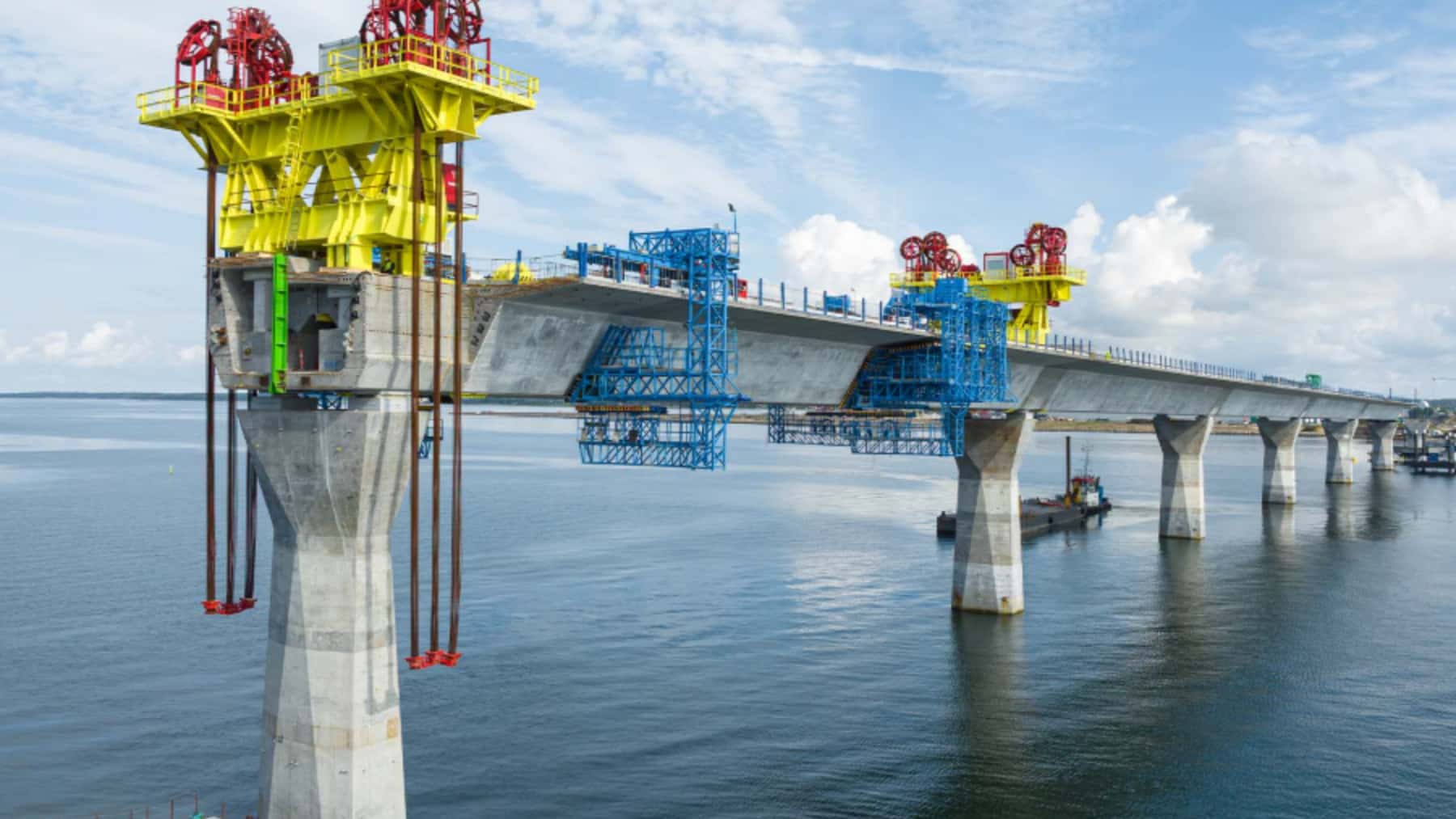 Puente de gran longitud en construcción sobre el mar con pilares de hormigón y estructuras técnicas.