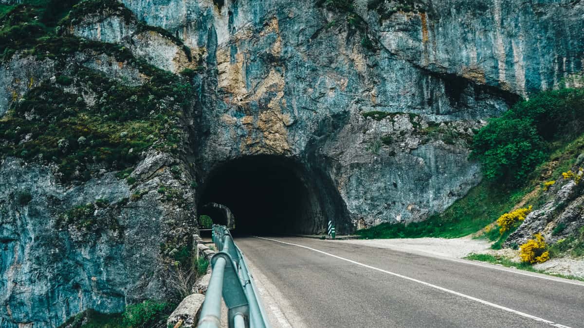 Carretera que atraviesa un túnel excavado en la roca en una zona montañosa de España.