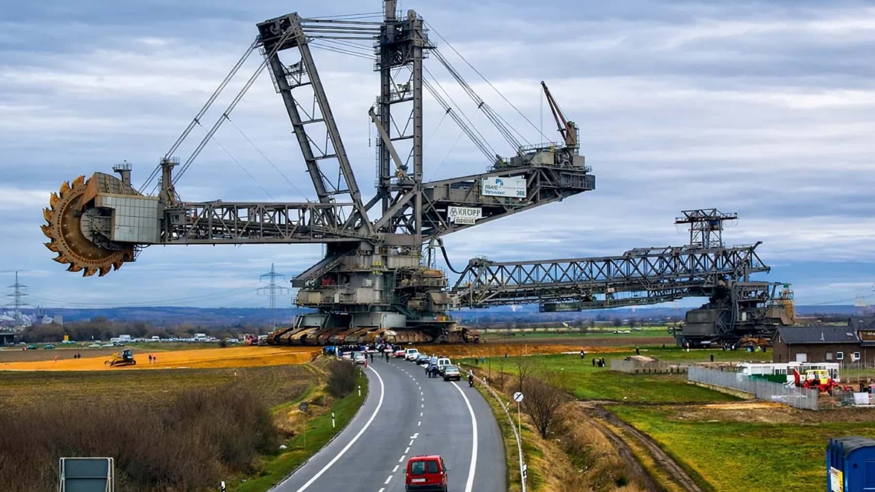 Excavadora minera gigante Bagger 293, fabricada por MAN TAKRAF, cruzando una carretera en una zona rural.