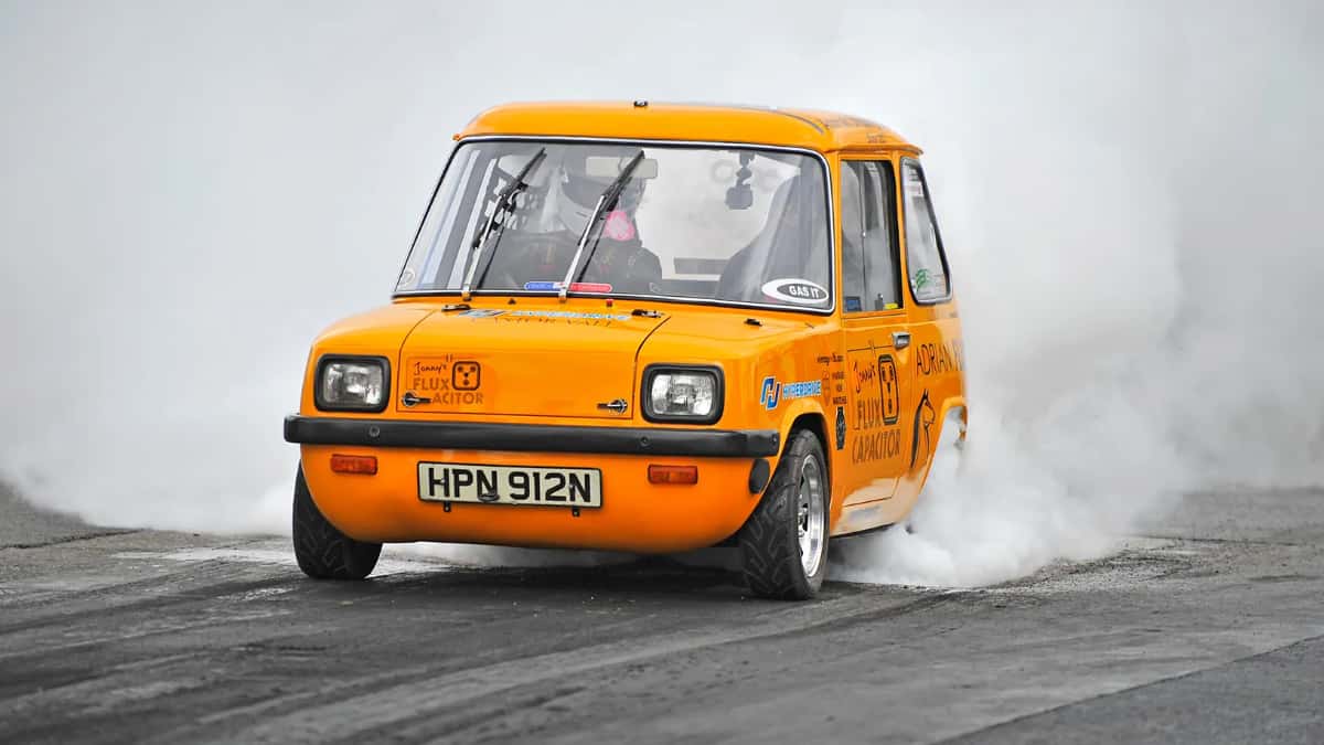 Un Enfield 8000 de color naranja circula sobre una pista mientras levanta humo de los neumáticos.