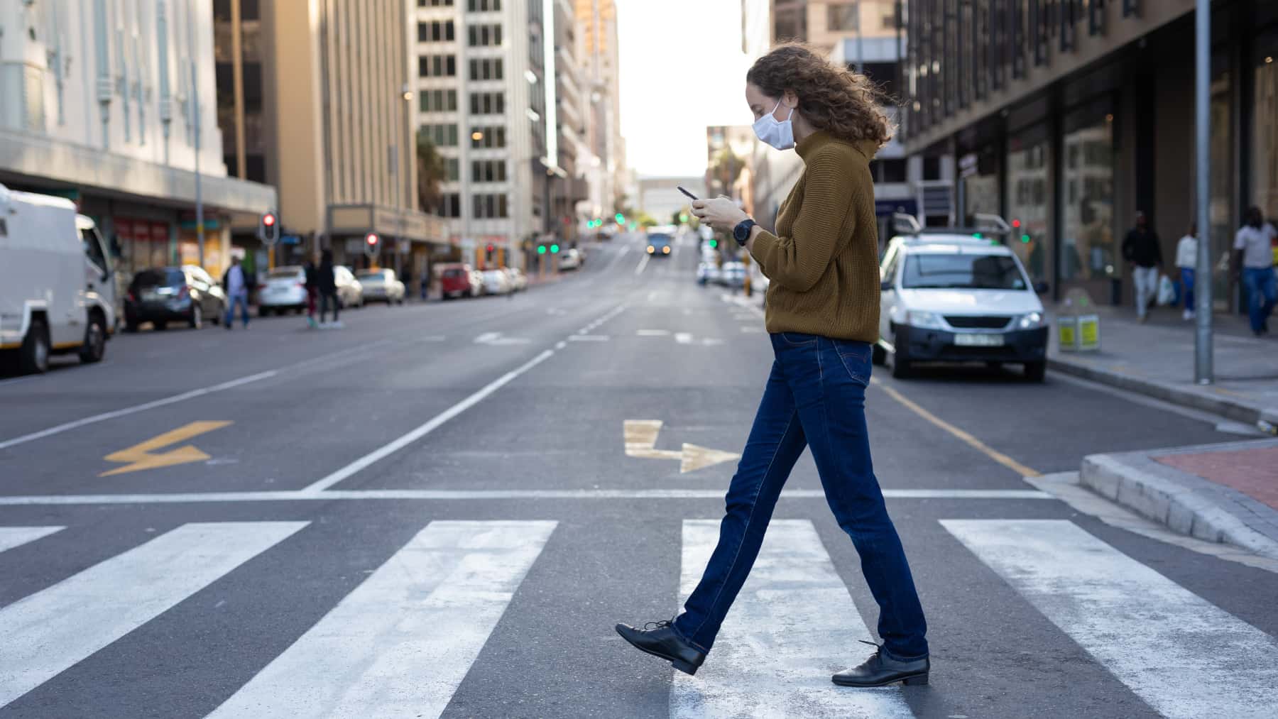 Mujer cruza la calle mirando el movil
