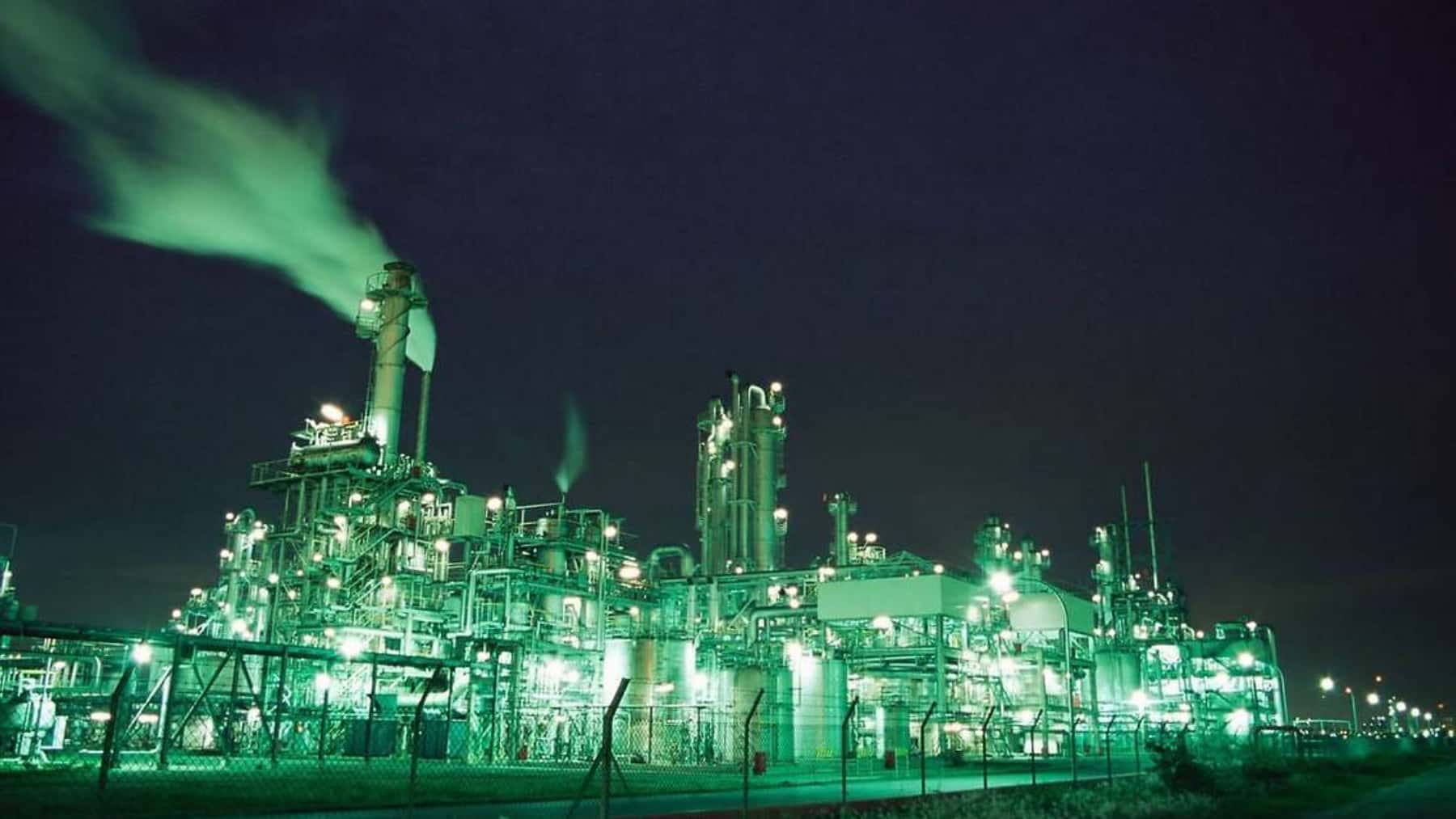 Planta industrial iluminada de noche en Kawasaki, Japón, con chimeneas y emisiones de vapor sobre las instalaciones.