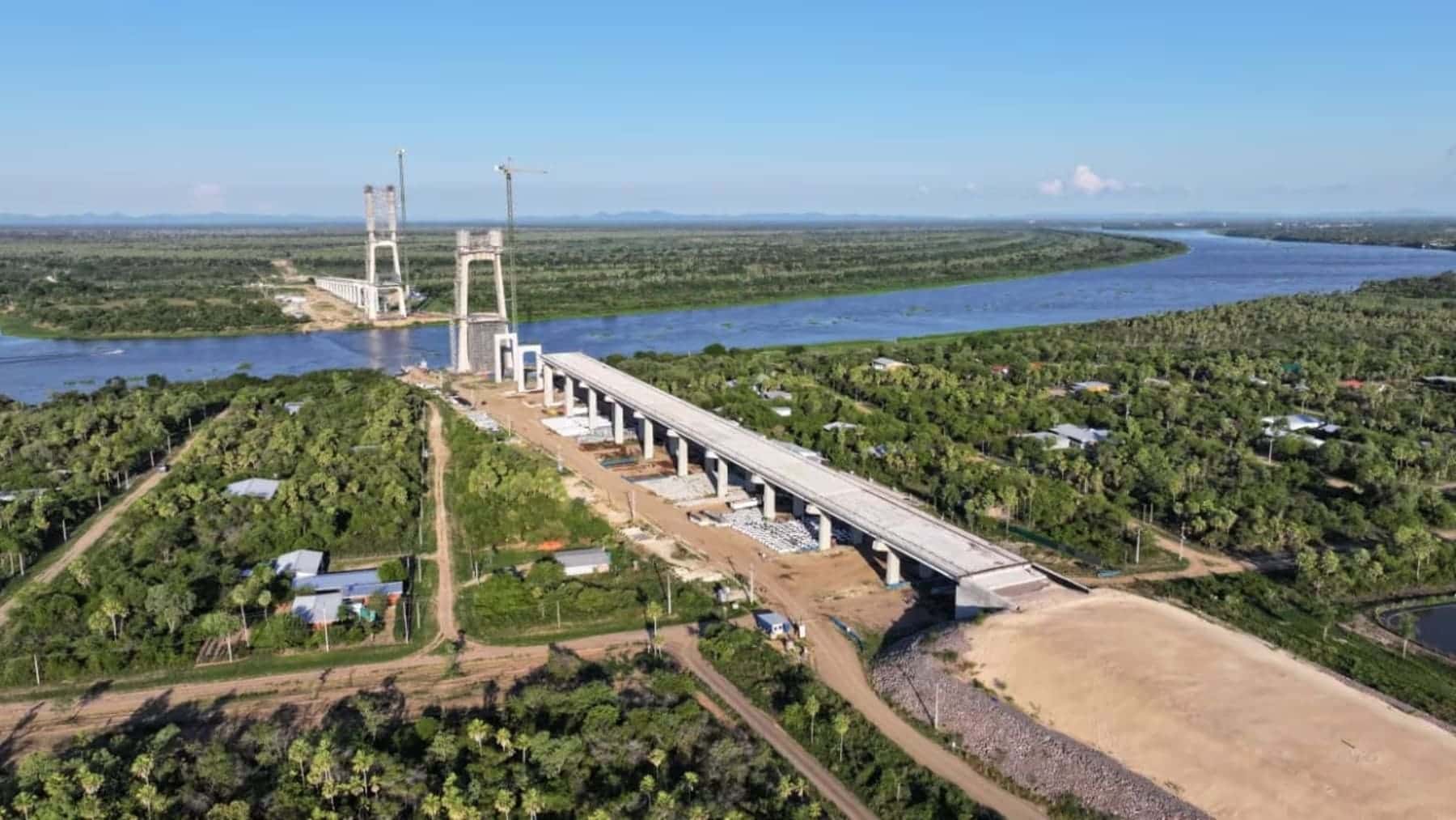 Puente en construcción sobre un gran río en una zona selvática, parte de un corredor de transporte entre el Atlántico y el Pacífico.