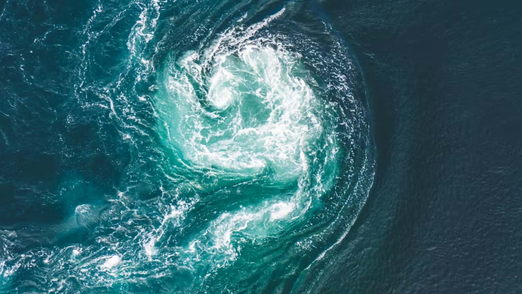 Remolino oceánico con corrientes de agua turquesa y espuma blanca visto desde el aire